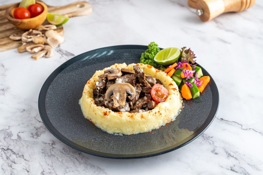 Plate of potato puree with mushrooms and vegetables